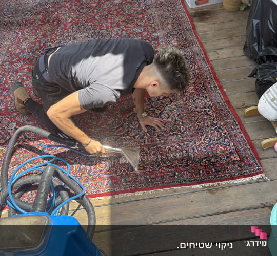 אדם מנקה שטיח עם מכונת ניקוי